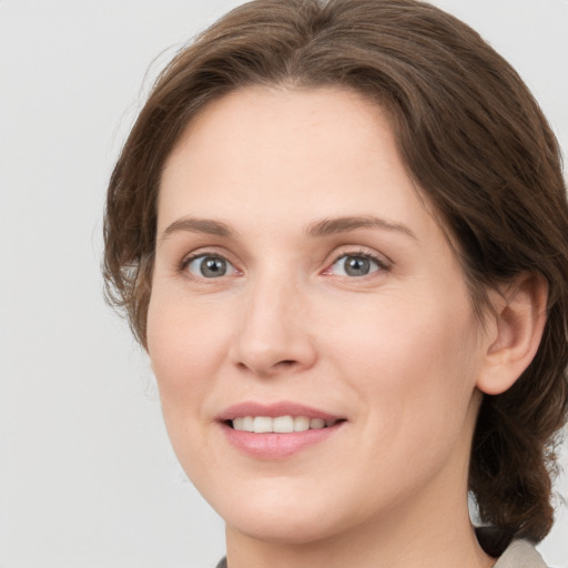 Joyful white young-adult female with medium  brown hair and grey eyes