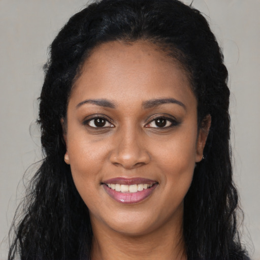 Joyful black young-adult female with long  brown hair and brown eyes