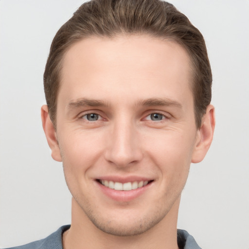 Joyful white young-adult male with short  brown hair and grey eyes