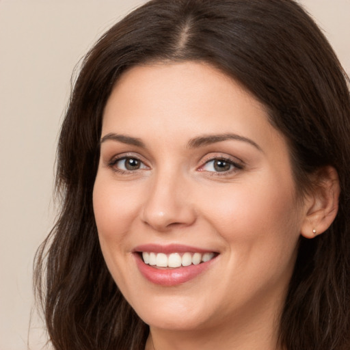 Joyful white young-adult female with long  brown hair and brown eyes