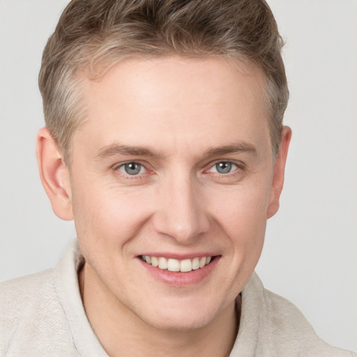 Joyful white young-adult male with short  brown hair and grey eyes