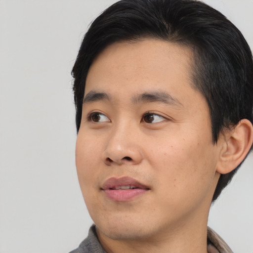 Joyful asian young-adult male with medium  black hair and brown eyes