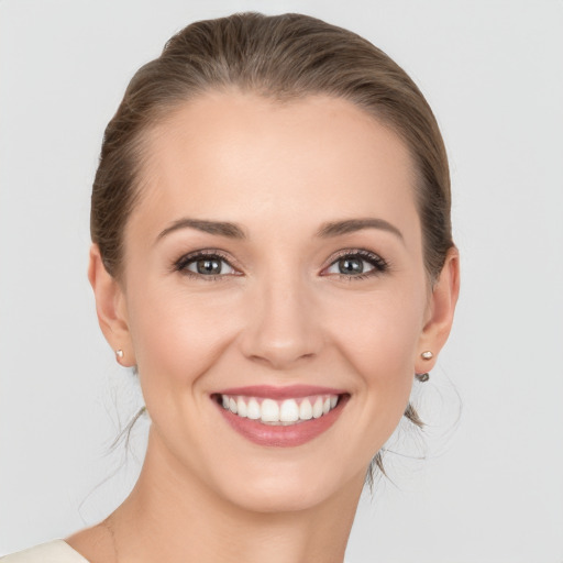 Joyful white young-adult female with medium  brown hair and grey eyes