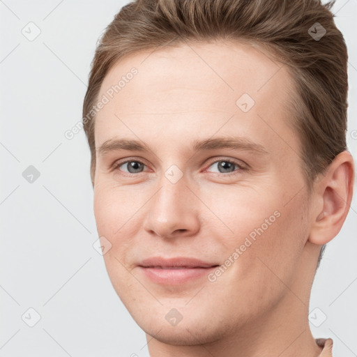 Joyful white young-adult male with short  brown hair and grey eyes