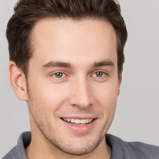 Joyful white young-adult male with short  brown hair and grey eyes