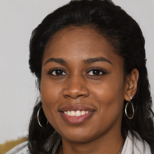 Joyful black young-adult female with long  black hair and brown eyes