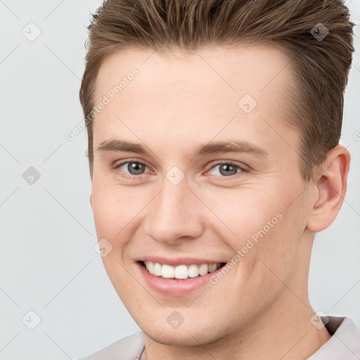 Joyful white young-adult male with short  brown hair and grey eyes