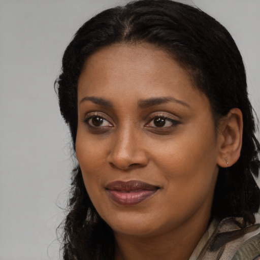 Joyful black young-adult female with long  brown hair and brown eyes