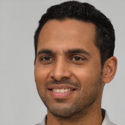 Joyful latino young-adult male with short  black hair and brown eyes