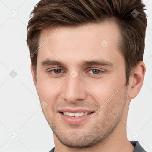 Joyful white young-adult male with short  brown hair and grey eyes