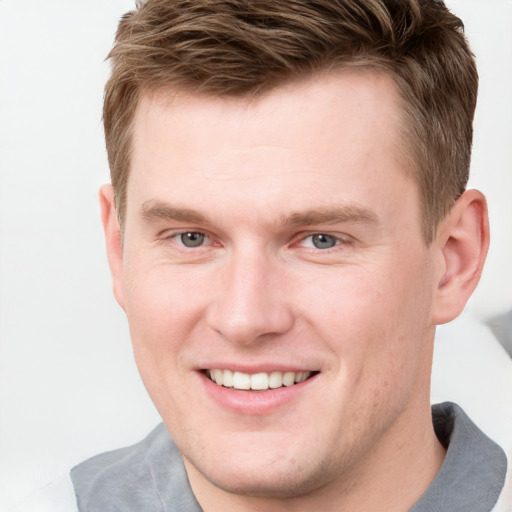 Joyful white young-adult male with short  brown hair and grey eyes