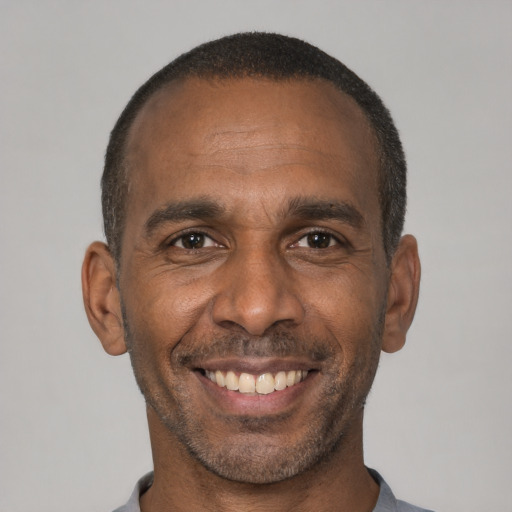Joyful black adult male with short  black hair and brown eyes