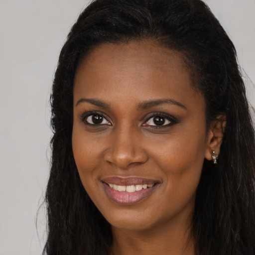 Joyful black young-adult female with long  brown hair and brown eyes