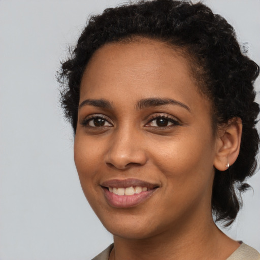 Joyful black young-adult female with short  black hair and brown eyes