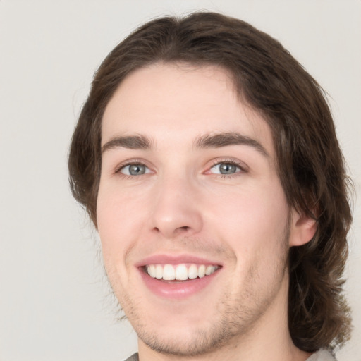 Joyful white young-adult male with medium  brown hair and green eyes