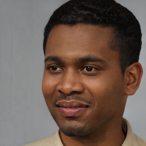 Joyful black young-adult male with short  black hair and brown eyes