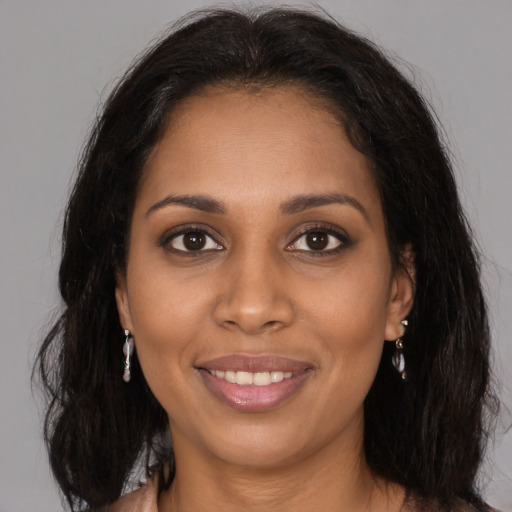 Joyful black young-adult female with long  brown hair and brown eyes