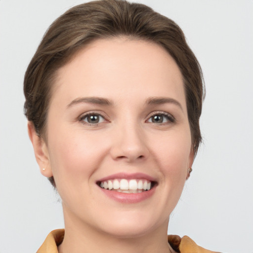 Joyful white young-adult female with short  brown hair and grey eyes