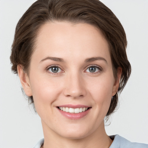 Joyful white young-adult female with medium  brown hair and grey eyes