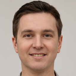 Joyful white young-adult male with short  brown hair and grey eyes