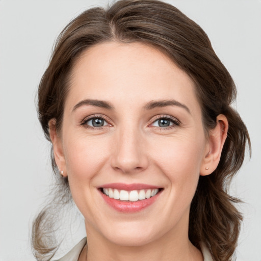 Joyful white young-adult female with medium  brown hair and grey eyes