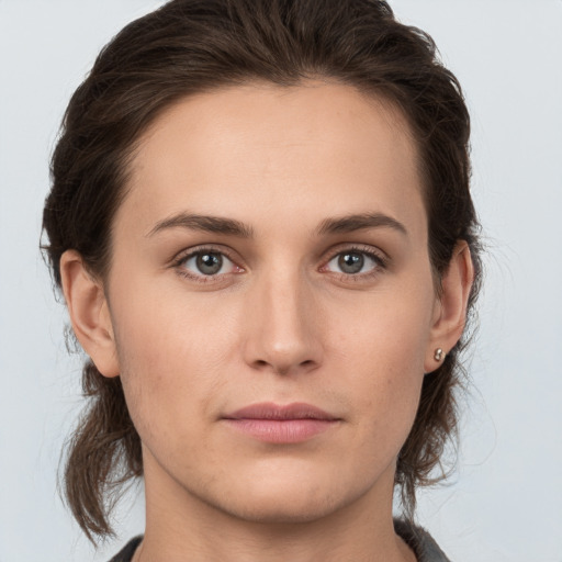 Joyful white young-adult female with medium  brown hair and grey eyes