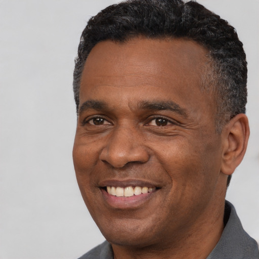 Joyful black adult male with short  black hair and brown eyes