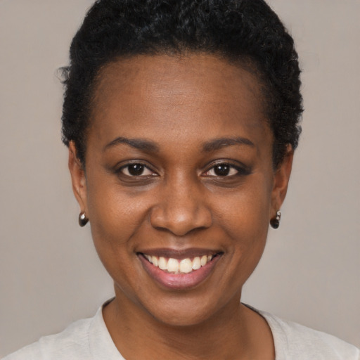Joyful black young-adult female with short  black hair and brown eyes