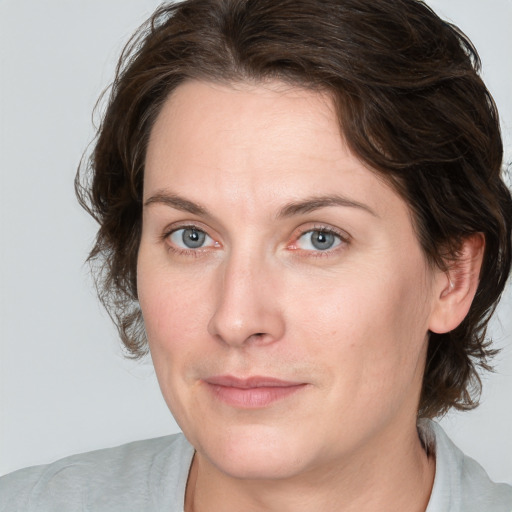 Joyful white adult female with medium  brown hair and blue eyes