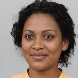 Joyful black young-adult female with long  brown hair and brown eyes