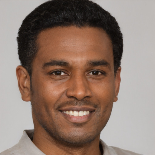 Joyful black young-adult male with short  black hair and brown eyes