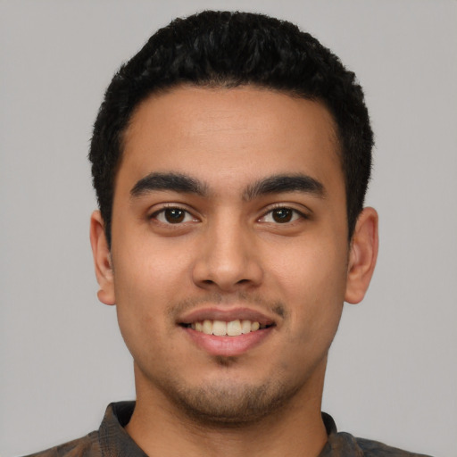 Joyful latino young-adult male with short  black hair and brown eyes