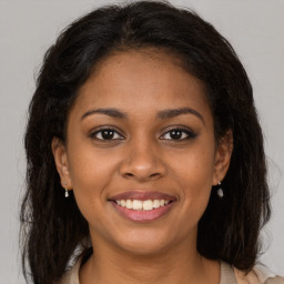 Joyful black young-adult female with long  brown hair and brown eyes