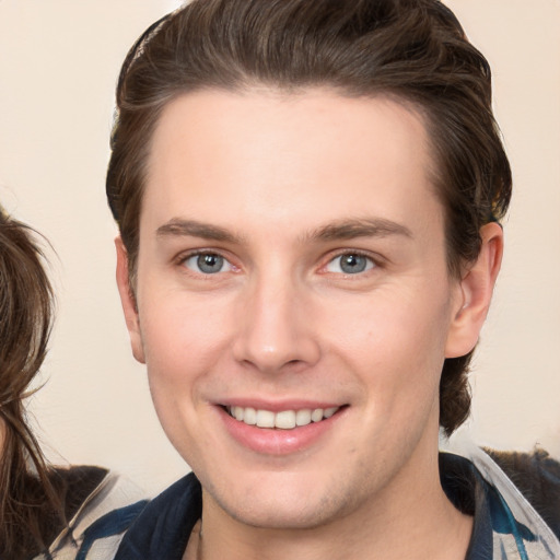 Joyful white young-adult male with medium  brown hair and grey eyes