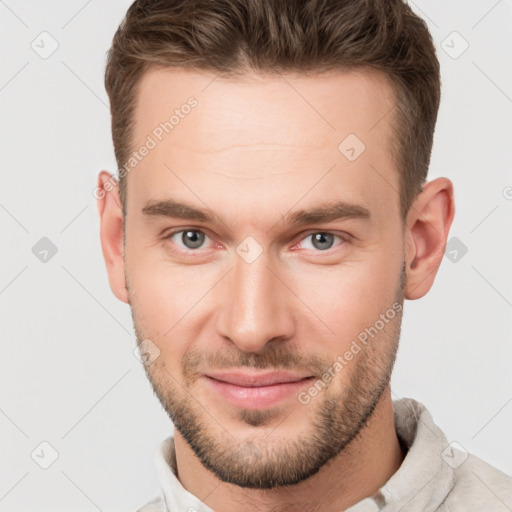 Joyful white young-adult male with short  brown hair and grey eyes