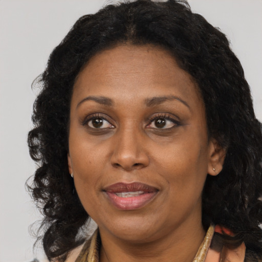 Joyful black adult female with long  brown hair and brown eyes