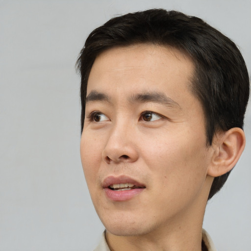 Joyful asian adult male with short  black hair and brown eyes