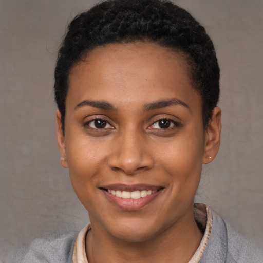 Joyful black young-adult female with short  black hair and brown eyes
