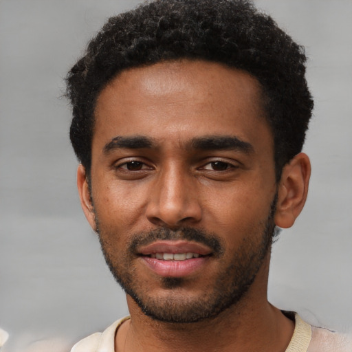 Joyful black young-adult male with short  black hair and brown eyes