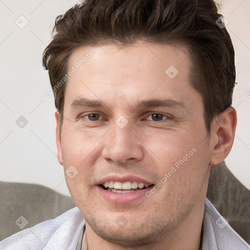 Joyful white young-adult male with short  brown hair and grey eyes