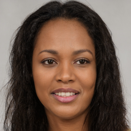 Joyful black young-adult female with long  brown hair and brown eyes