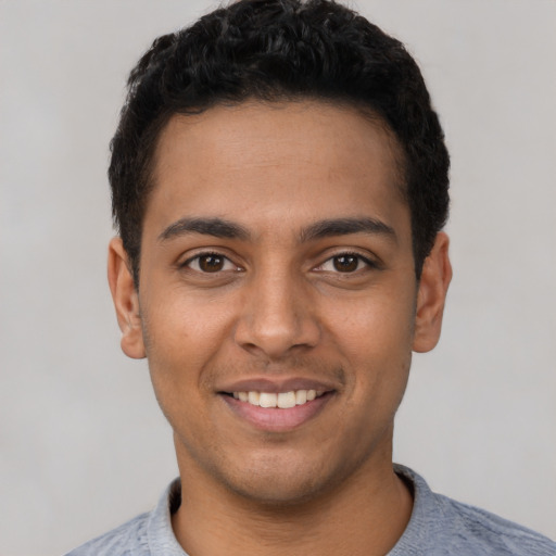 Joyful latino young-adult male with short  black hair and brown eyes
