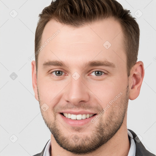 Joyful white young-adult male with short  brown hair and grey eyes