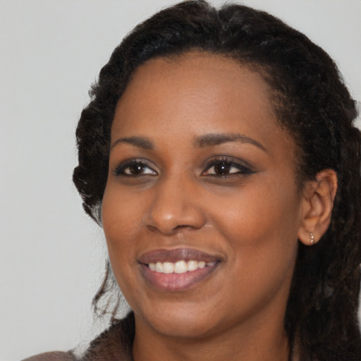 Joyful black young-adult female with long  black hair and brown eyes