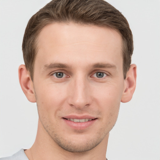 Joyful white young-adult male with short  brown hair and grey eyes