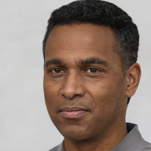Joyful black adult male with short  black hair and brown eyes