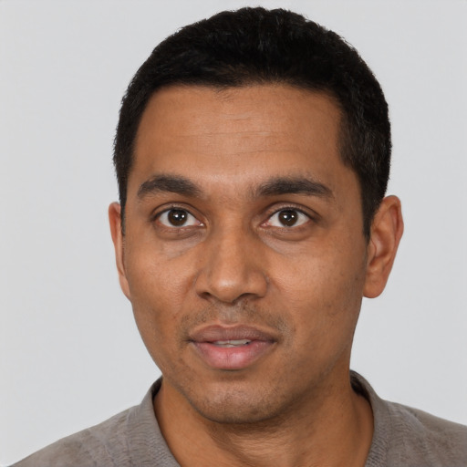 Joyful black young-adult male with short  black hair and brown eyes