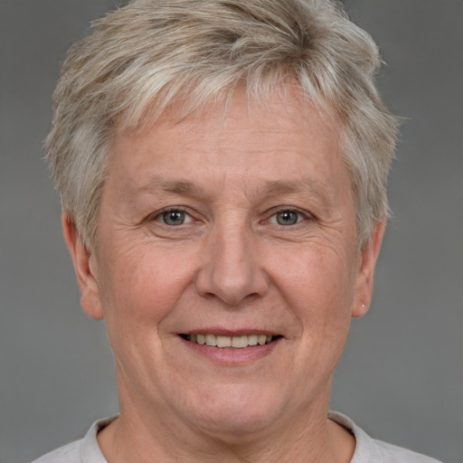 Joyful white middle-aged female with short  blond hair and grey eyes