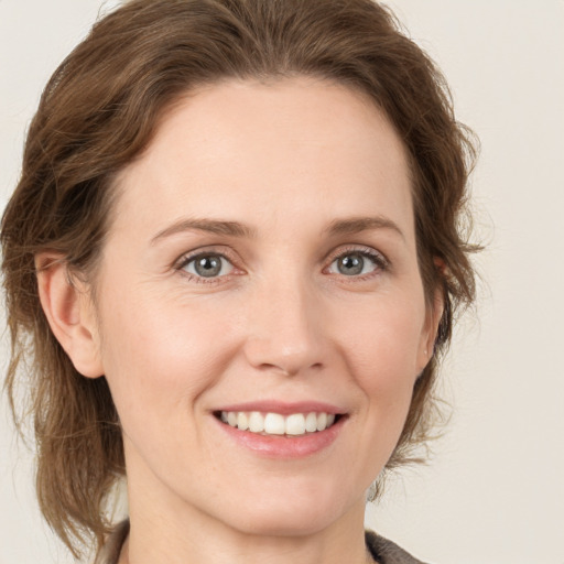 Joyful white young-adult female with medium  brown hair and grey eyes