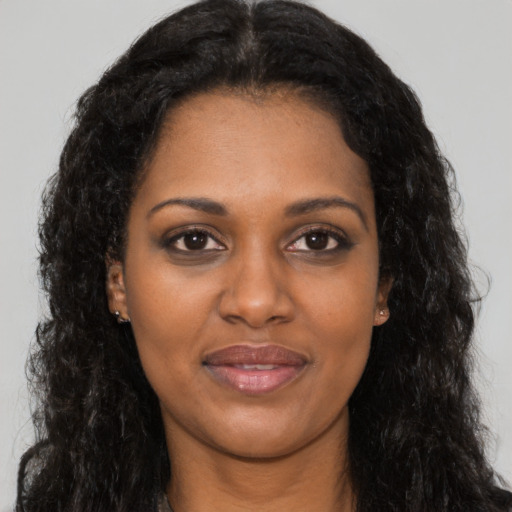 Joyful black young-adult female with long  brown hair and brown eyes